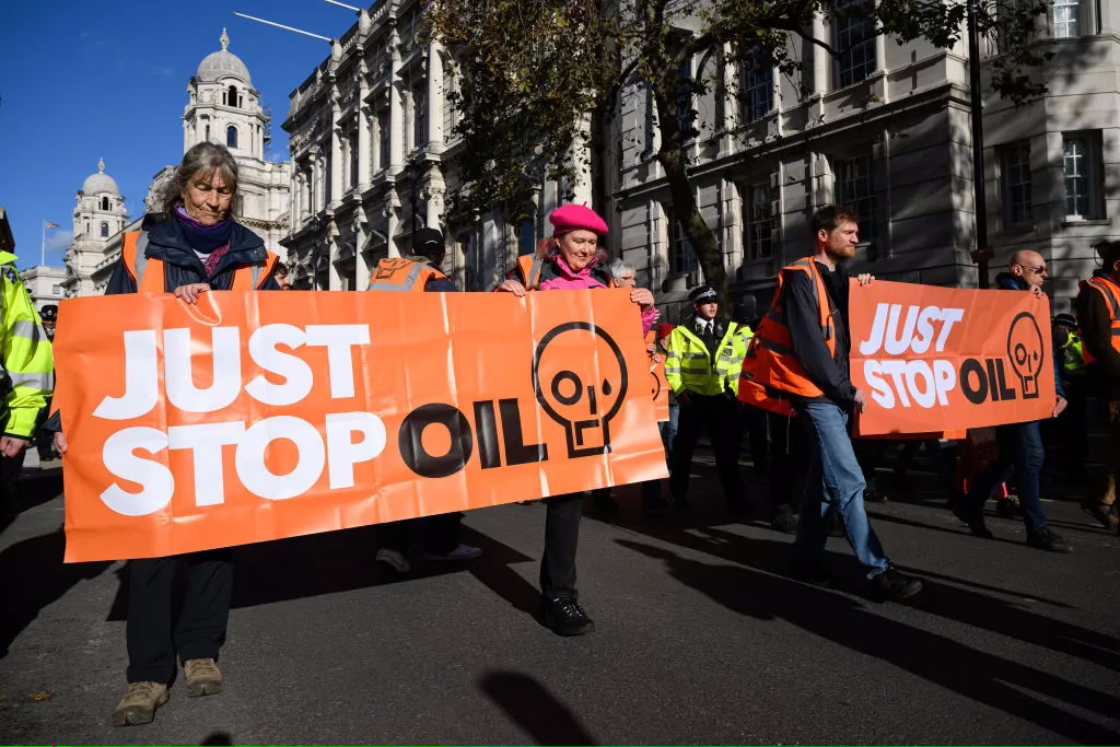 A group of people holding signs that say " just stop oil ".