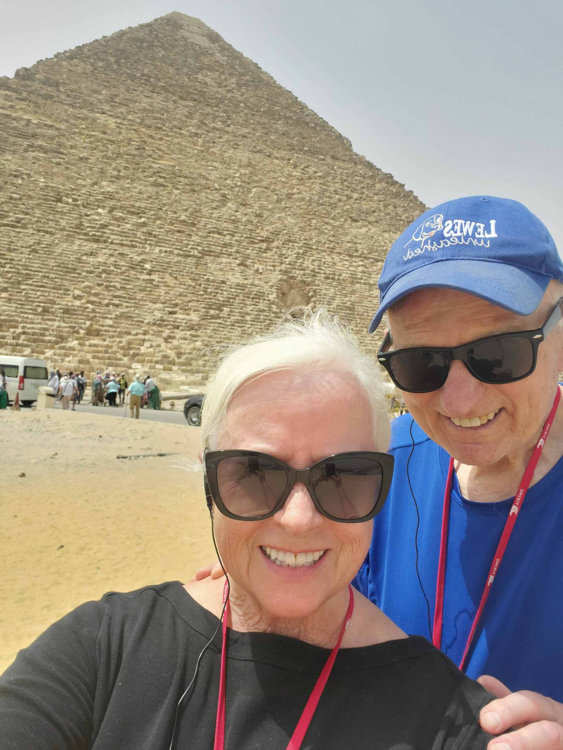 A man and woman posing for a picture in front of the pyramids.