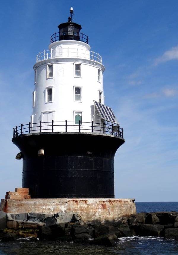 A lighthouse with a black and white structure on top of it.